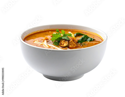 Creamy thai curry soup in white ceramic bowl with lime, basil, and cilantro garnish
