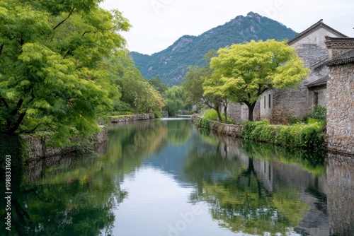 ancient chinese village by the river, with stone houses and lush greenery along its banks. the clear water reflects the surrounding mountains and trees