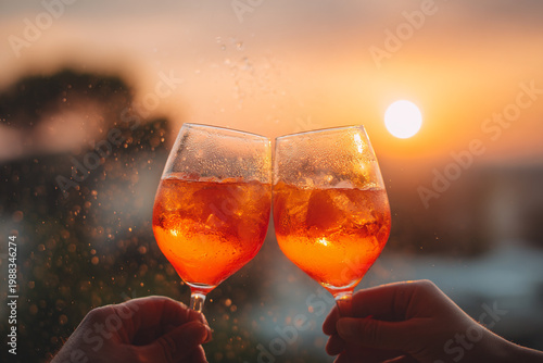 Two Hands Holding Orange Cocktail Glasses Cheering at Sunset Outdoors