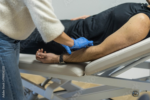 Une infirmière avec des gants bleus, nettoie le bras d'un patient avant une piqûre et des soins