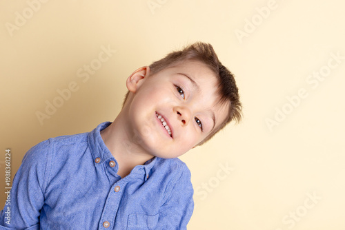 Boy of three years in a blue shirt on a yellow background. Emotional portrait.