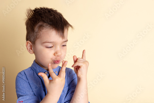 Boy of three years in a blue shirt on a yellow background. Emotional portrait.