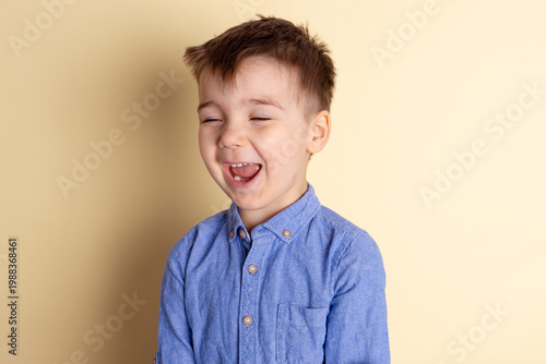 Boy of three years in a blue shirt on a yellow background. Emotional portrait.