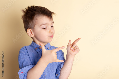 Boy of three years in a blue shirt on a yellow background. Emotional portrait.