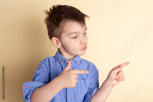 Boy of three years in a blue shirt on a yellow background. Emotional portrait.