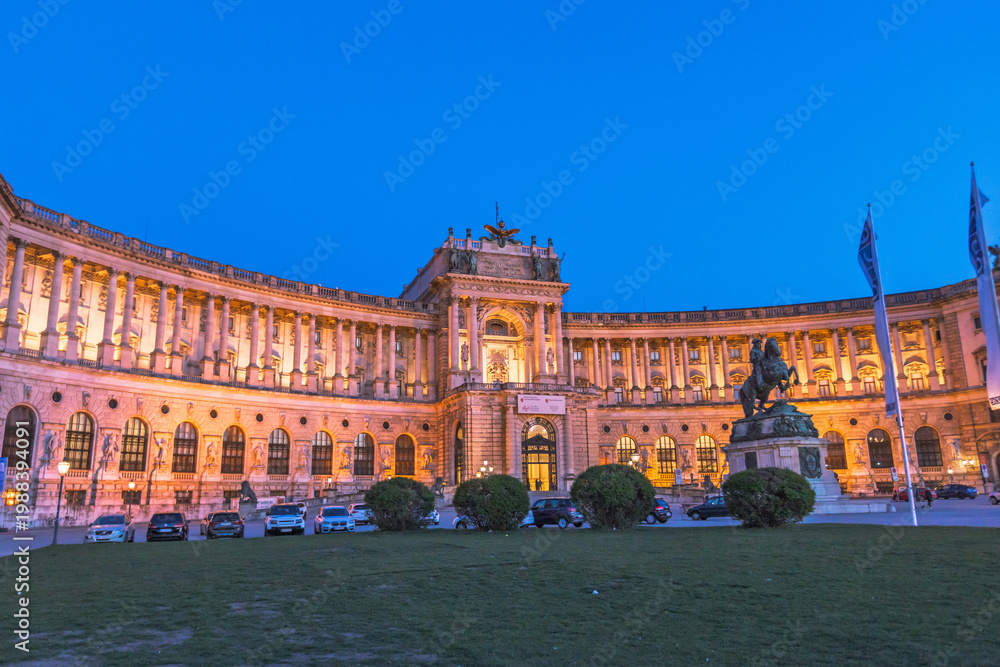 Obraz premium Night view of the illuminated Neue Burg wing of Hofburg Palace and Prince Eugene statue in Vienna.