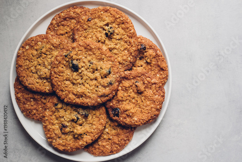 Freshly baked homemade oatmeal cranberry cookies on plate on grey background, top down view. Healthy sweet food. Copy space for text.