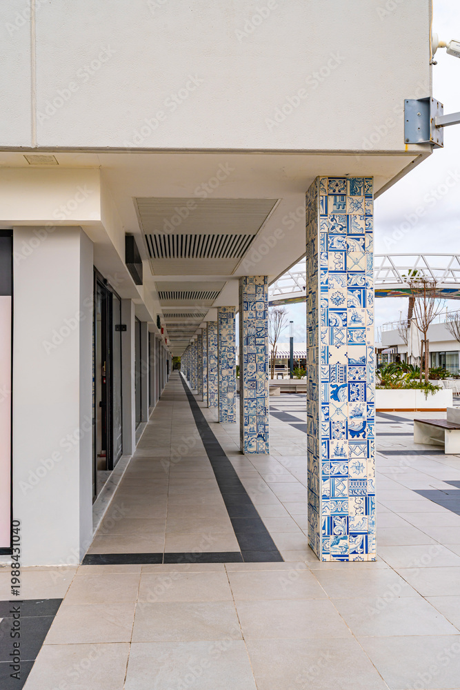 Obraz premium Contemporary walkway with decorative azulejo tile columns in Cascais, Portugal. Urban architectural scene with patterned ceramics, clean lines and coastal shopping area atmosphere.