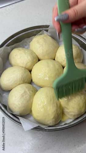 Brushing buns with egg before baking