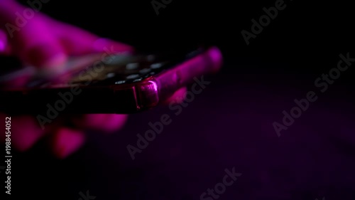 Hands hold a mobile phone illuminated by flashing red and blue strobe lights in the darkness. Concept of contacting emergency services, recording a crime scene, or reporting an accident.