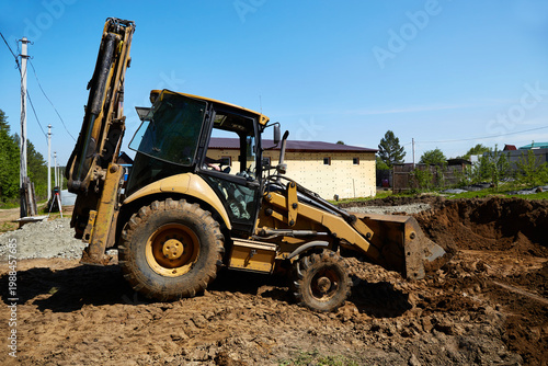 Konstfotografi Backhoe loader excavating a large foundation pit at a residential construction s