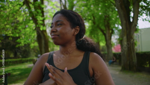 African American woman standing in park holding her head and showing visible stress, worry and preoccupation creating tense and emotionally charged outdoor lifestyle moment in natural environment