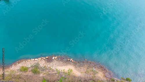 Photography March 28 2026 Calm blue water meets curved strip of rocky coast.