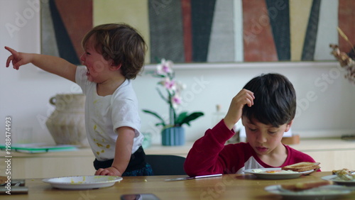 Foto Young children sitting at table during mealtime with one child crying and pointi