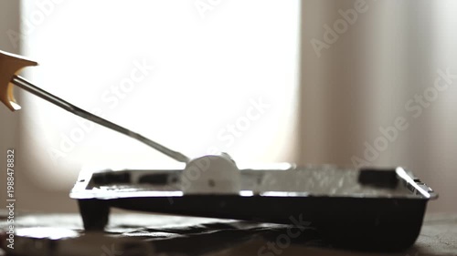 Close-up of Paint Roller Dipped into White Paint in Tray, Preparing for Wall or Door Painting, 4K 10-bit