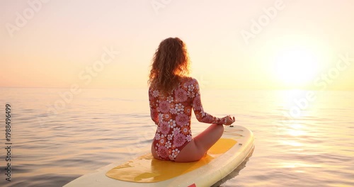 A happy young woman walking on a sup board by the sea during her summer vacation. Slow motion