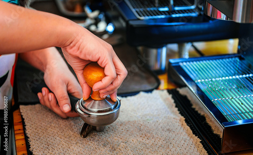 фотографія Close-up of barista hand using tamper to press ground coffee in portafilter bask