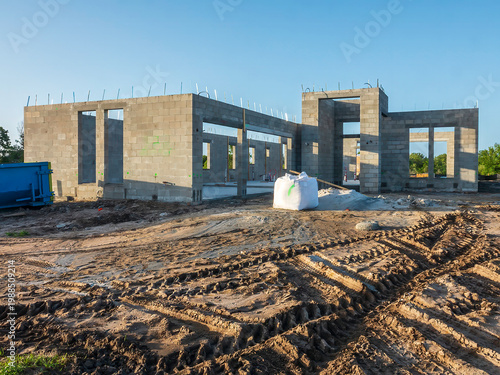 Hurricane-resistant house under construction, with track marks and an 80-pound (36.29-kilogram) bag of masonry cement in front of the concrete shell, in a suburban residential development in Florida