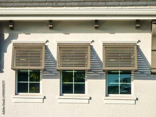 Row of three half Bahama shutters on front windows of a new house in an upscale residential development on a sunny morning in southwest Florida. Decorative aluminum, non-impact.
