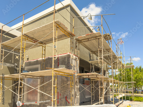 Modular scaffolding for exterior work on renovation of the facade of a defunct restaurant for a new corner attraction in a suburban town center on a sunny day in Florida. Motifs of adaptive reuse.