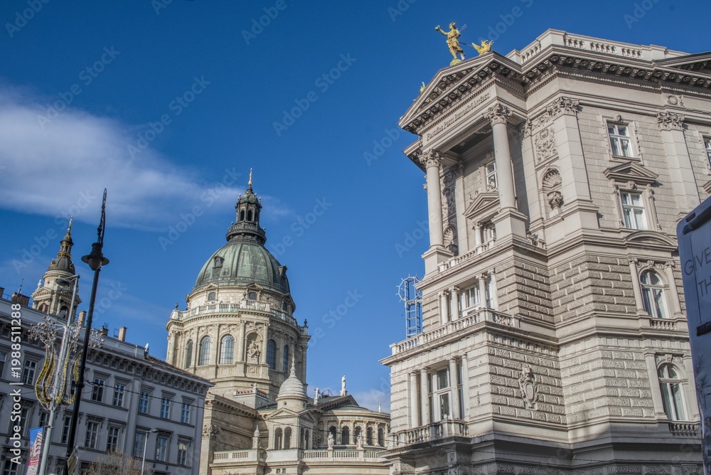Obraz premium Dome and curved colonnade of St. Stephen's Basilica in Budapest against a bright blue sky.