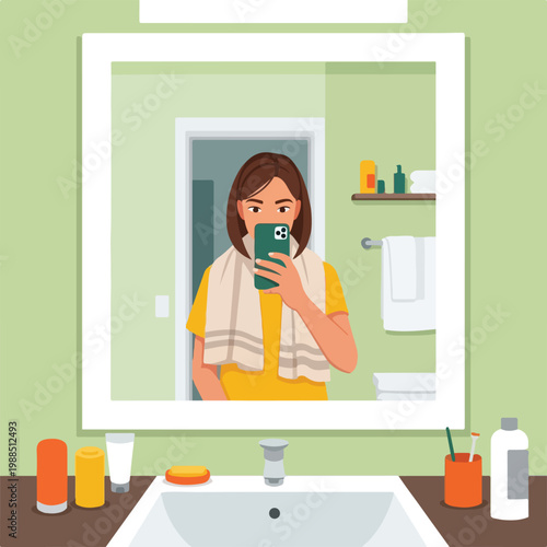 A woman takes a selfie in a bathroom mirror with a towel around her neck