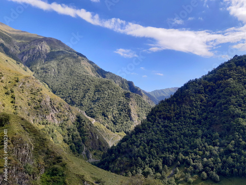 Obraz na plátne Dramatic mountain valley with convergent slopes and a long cloud in the Caucasus