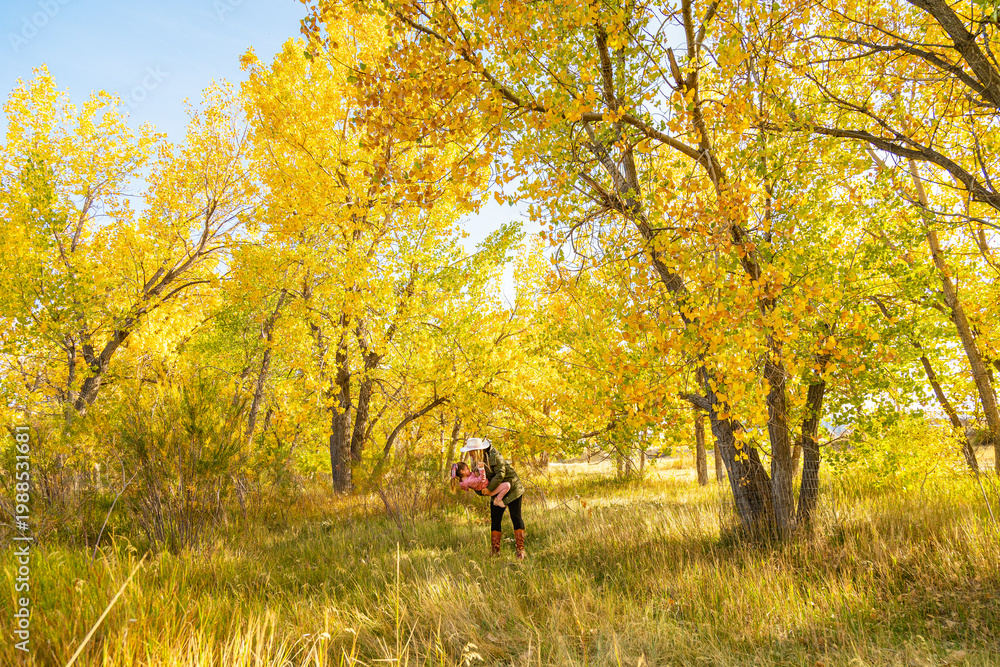 Fototapeta premium Woman Holding Child in Golden Aspen Forest During Peak Fall Season
