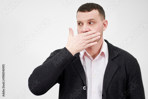 Fotografia portrait of man with hand over his mouth looking aside, stunned and speechless c