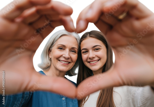 A smiling grandmother and her granddaughter forming a heart shape with their hands isolated on transparent background