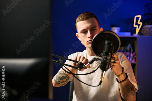 Foto Young adult Caucasian man adjusting podcast microphone while preparing livestrea