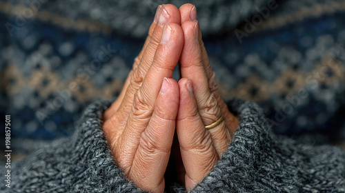 Closeup of praying hands with a patterned sweater.