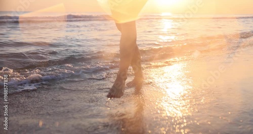 Happy woman is walking on the sandy beach in a red dress against sunrise. Slow motion