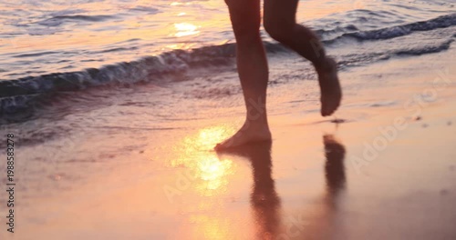 Happy woman is walking on the sandy beach in a red dress against sunrise. Slow motion