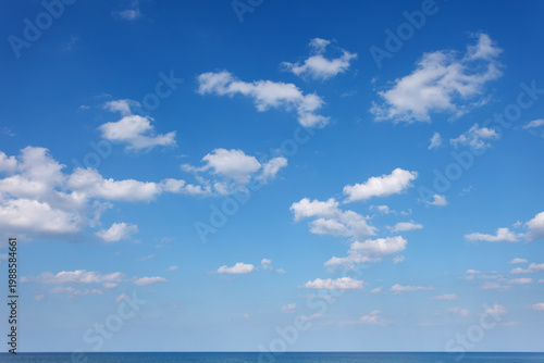 Blue sky with small white clouds over the sea