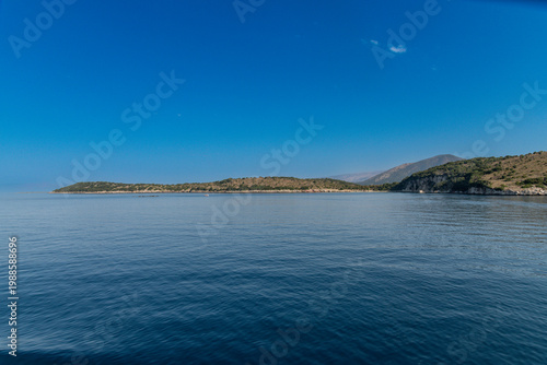 Konstfotografi Calm sea with rocky coastline and distant hills