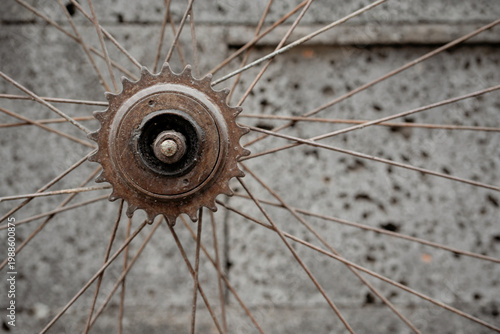 Close up of an old rusted bicycle freewheel gear and spokes on a textured volcanic rock background. Vintage bike parts.