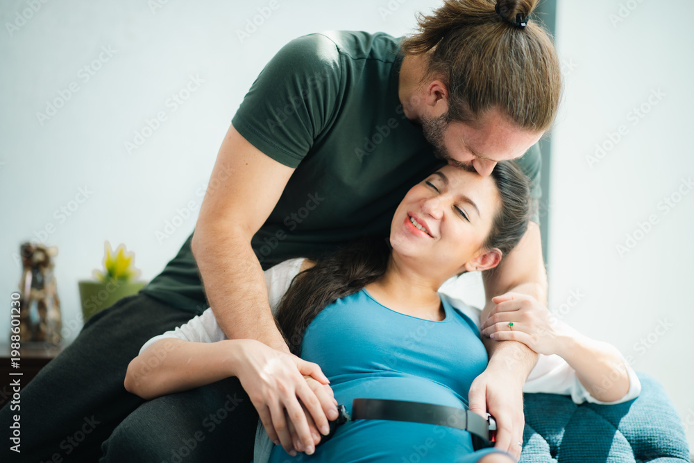Obraz premium Father's Day Concept, pregnant couple in home embrace affectionate partner support smiling pregnant woman intimate family moment maternity care love tenderness domestic scene