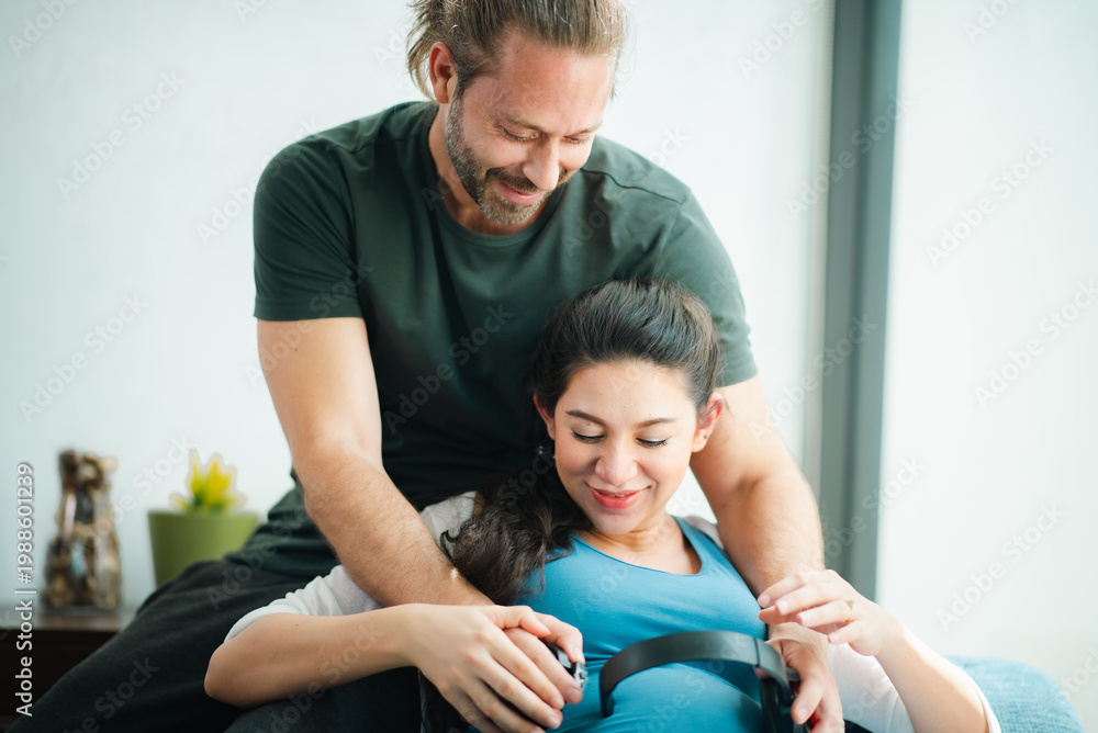 Fototapeta premium Father's Day Concept, pregnant woman receiving prenatal massage from therapist in bright clinic