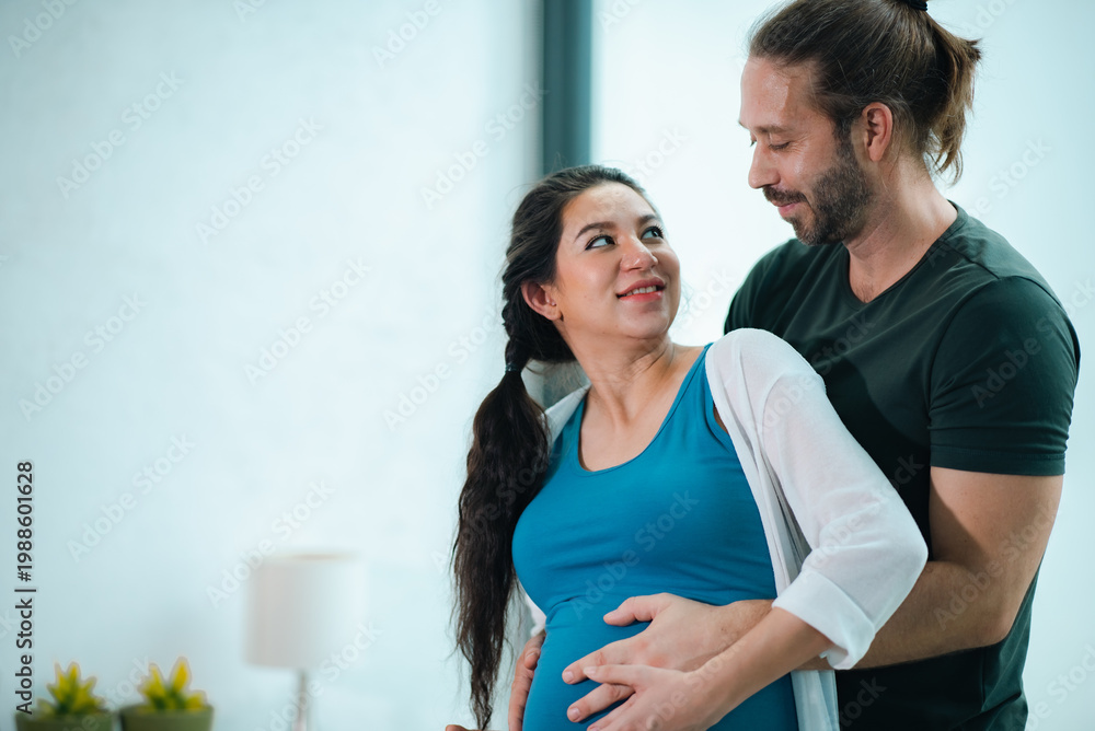 Naklejka premium Father's Day Concept, pregnant couple embracing in home, smiling at each other, romantic maternity moment