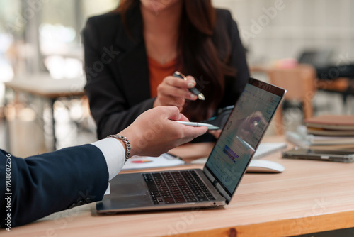 Konstfotografi Business people's hands pointing at a laptop screen, reviewing financial data an