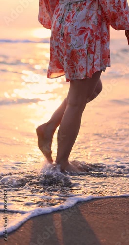 Happy woman is walking on the sandy beach in a red dress against sunrise. Slow motion
