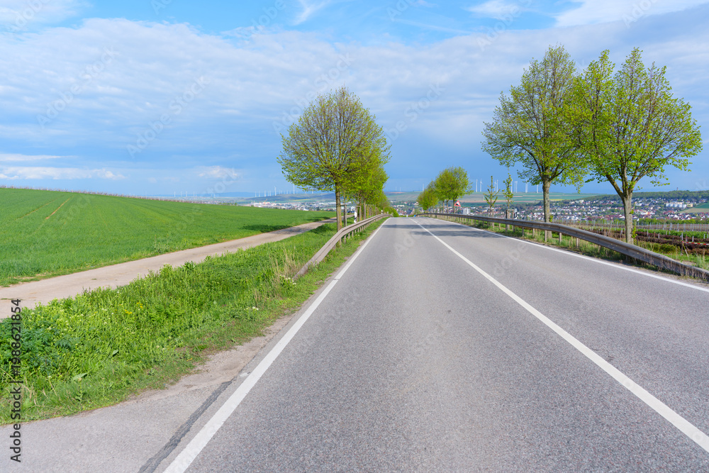 Obraz premium Scenic Road through German Countryside with Wind Turbines and Fields
