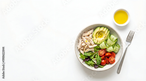 Healthy salad bowl with shredded chicken, avocado, cucumber, cherry tomatoes and mixed greens isolated on white background