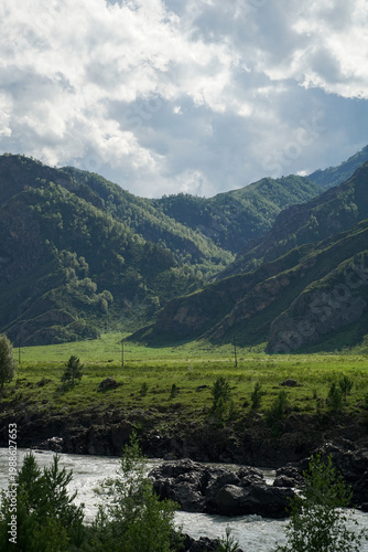 high mountains by the river and a cloudy sky