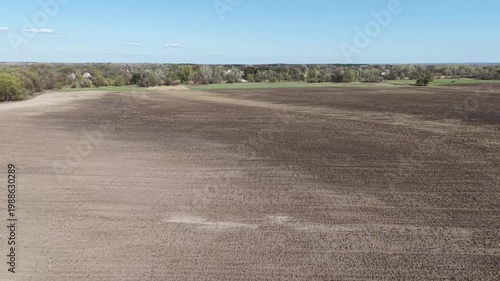 High angle drone view of vast agricultural field with signs of soil erosion. Dark fertile earth and light eroded patches on rolling hills in countryside. Environmental disaster and soil degradation