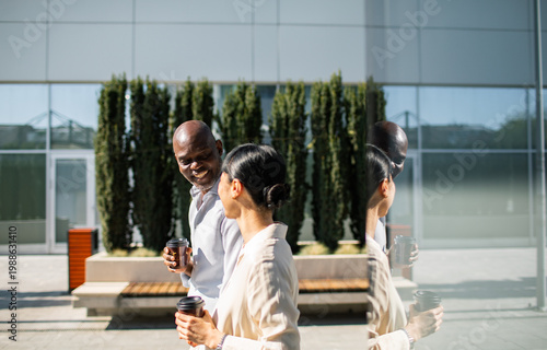 Coworkers walking with coffee outside modern office building