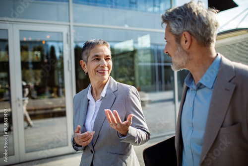 Two senior business professionals talking outside office
