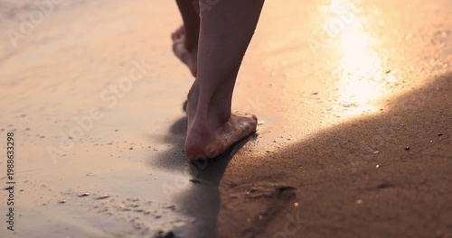 Happy woman is walking on the sandy beach in a red dress against sunrise. Slow motion