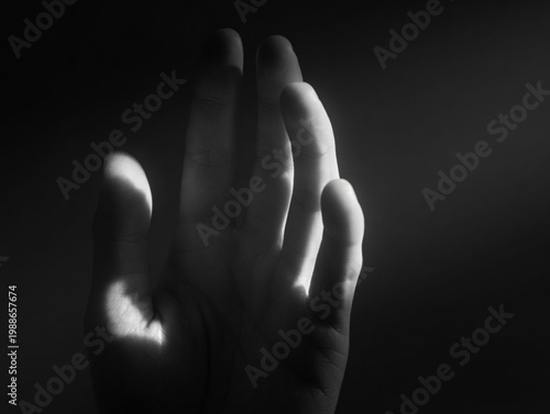 Obraz na płótnie Dramatic close-up of a human hand in high-contrast black and white, featuring cinematic lighting and deep shadows